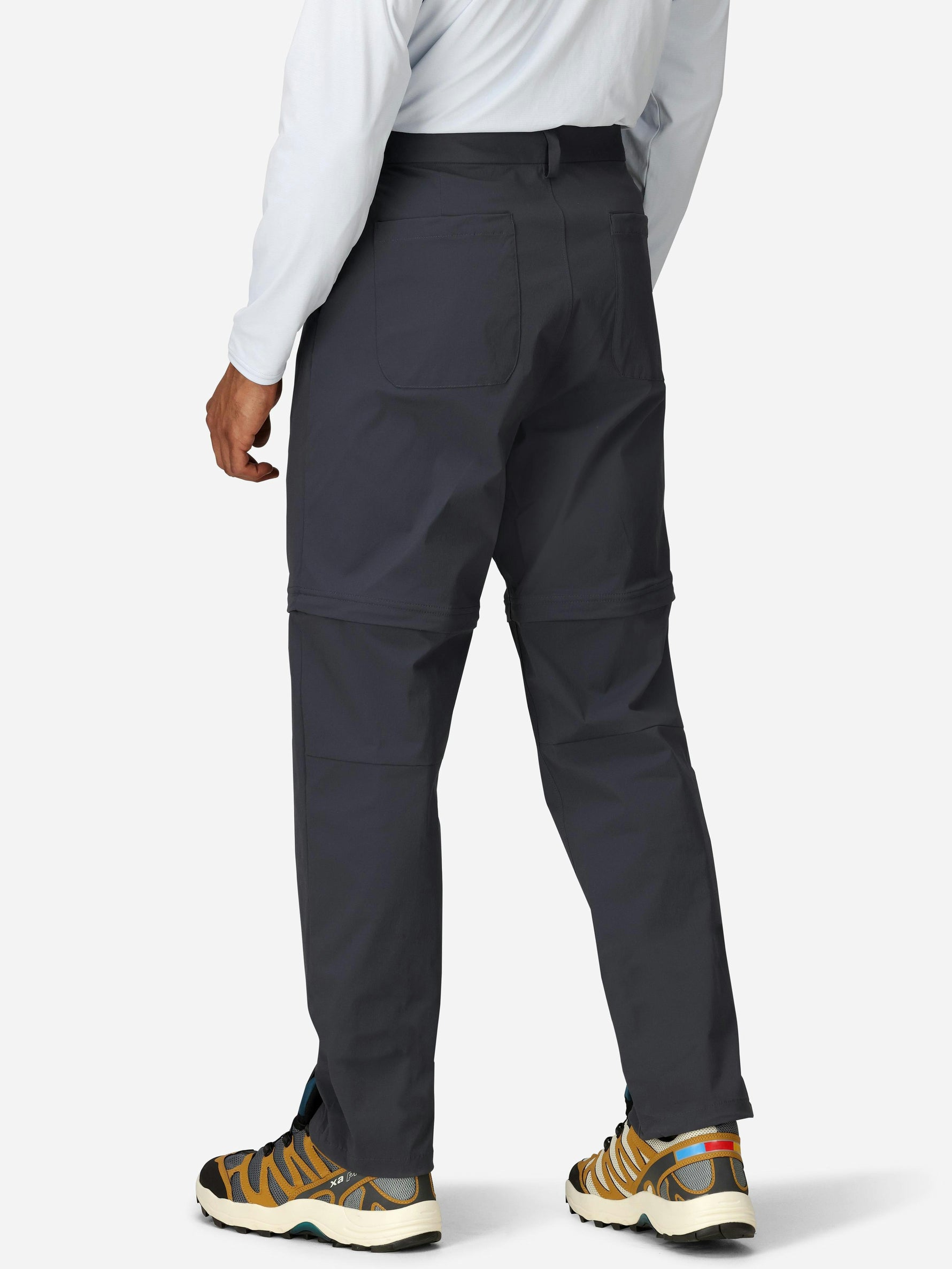 Man wearing dark gray convertible pants with zip-off legs and hiking shoes