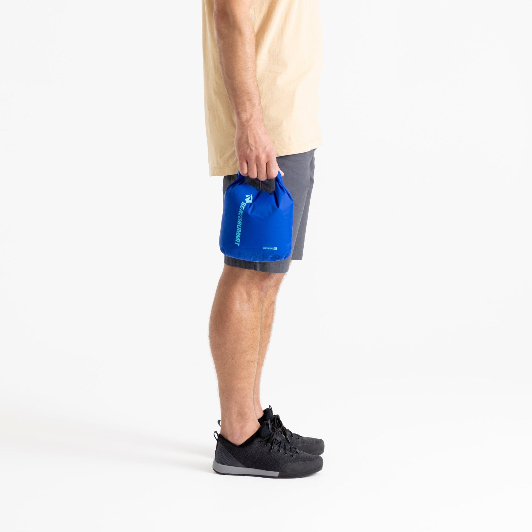 Person holding blue Sea To Summit lightweight dry bag while wearing gray shorts
