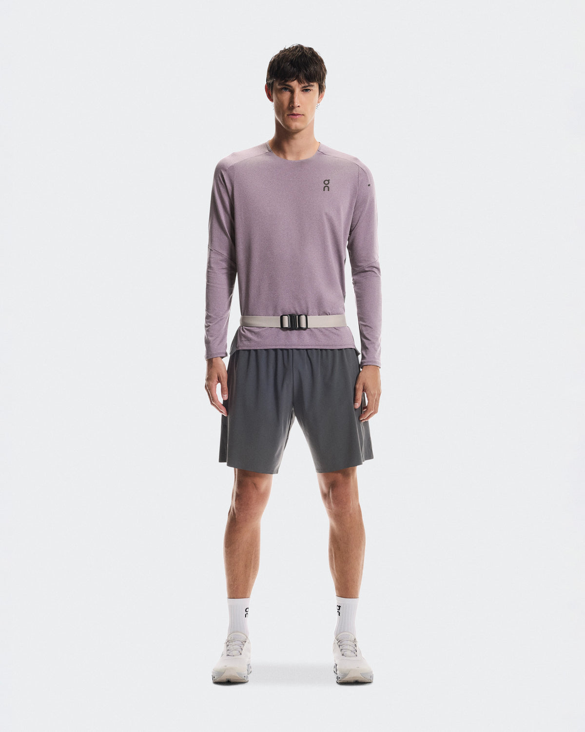 Male model wearing On Speed Belt in fog color over athletic long-sleeve and shorts