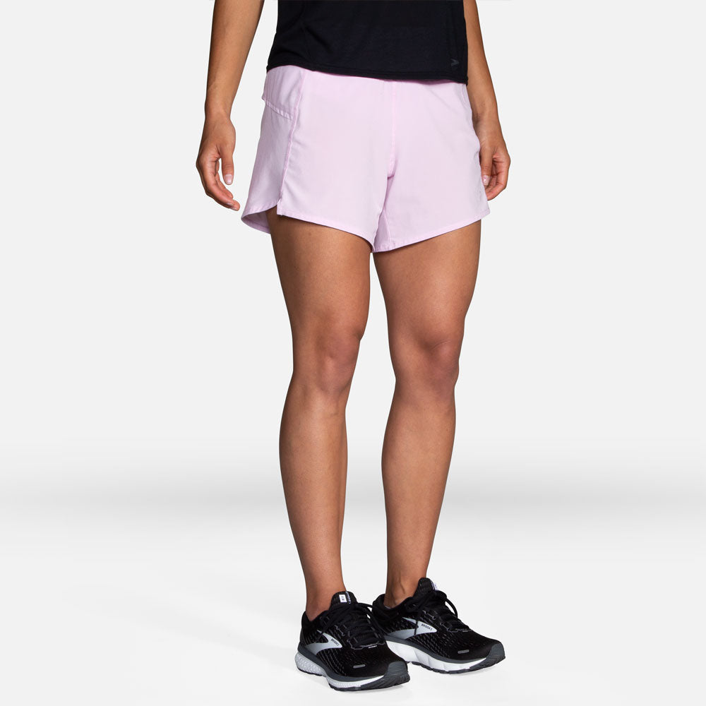 Woman wearing Brooks Chaser 5-inch running shorts in light pink with black top