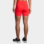 Back view of woman wearing red Brooks Method 5-inch athletic shorts