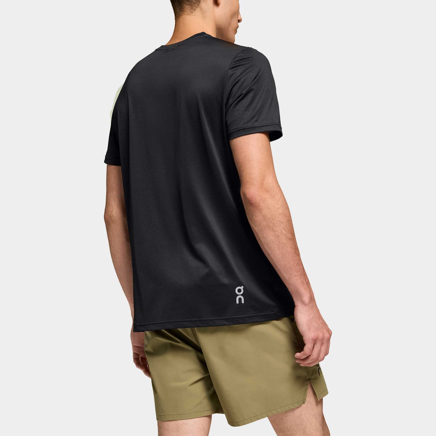 Back view of man wearing black On Core-T shirt with olive green shorts