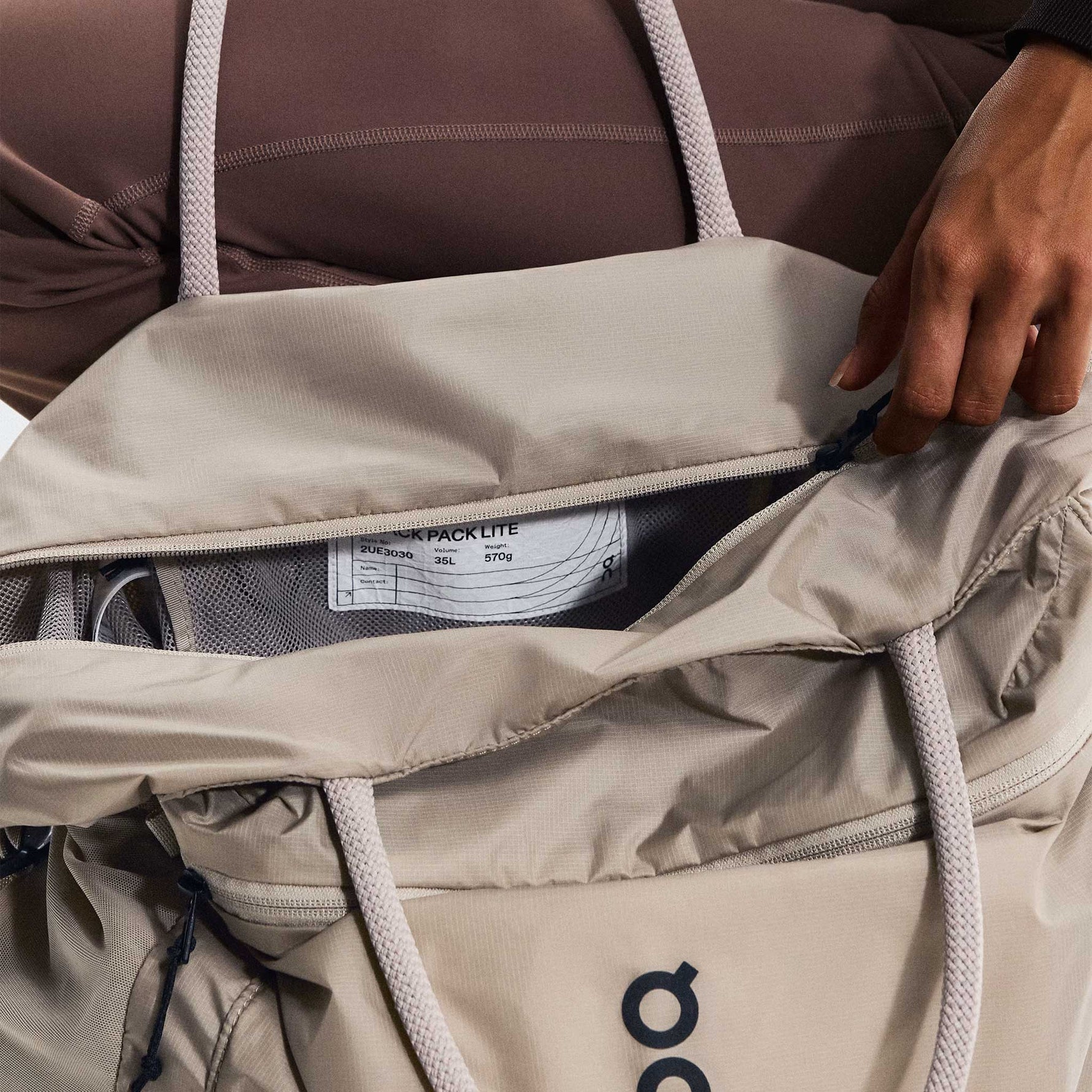 On Track Pack 35L Lite backpack in sand color showing internal compartment organization