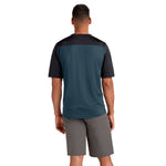 Back view of man wearing Dakine Syncline mountain bike jersey in galactic blue colorway