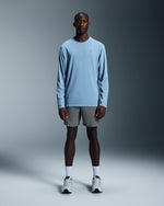 Male model wearing gray On 7-inch Core Shorts with blue long-sleeve shirt