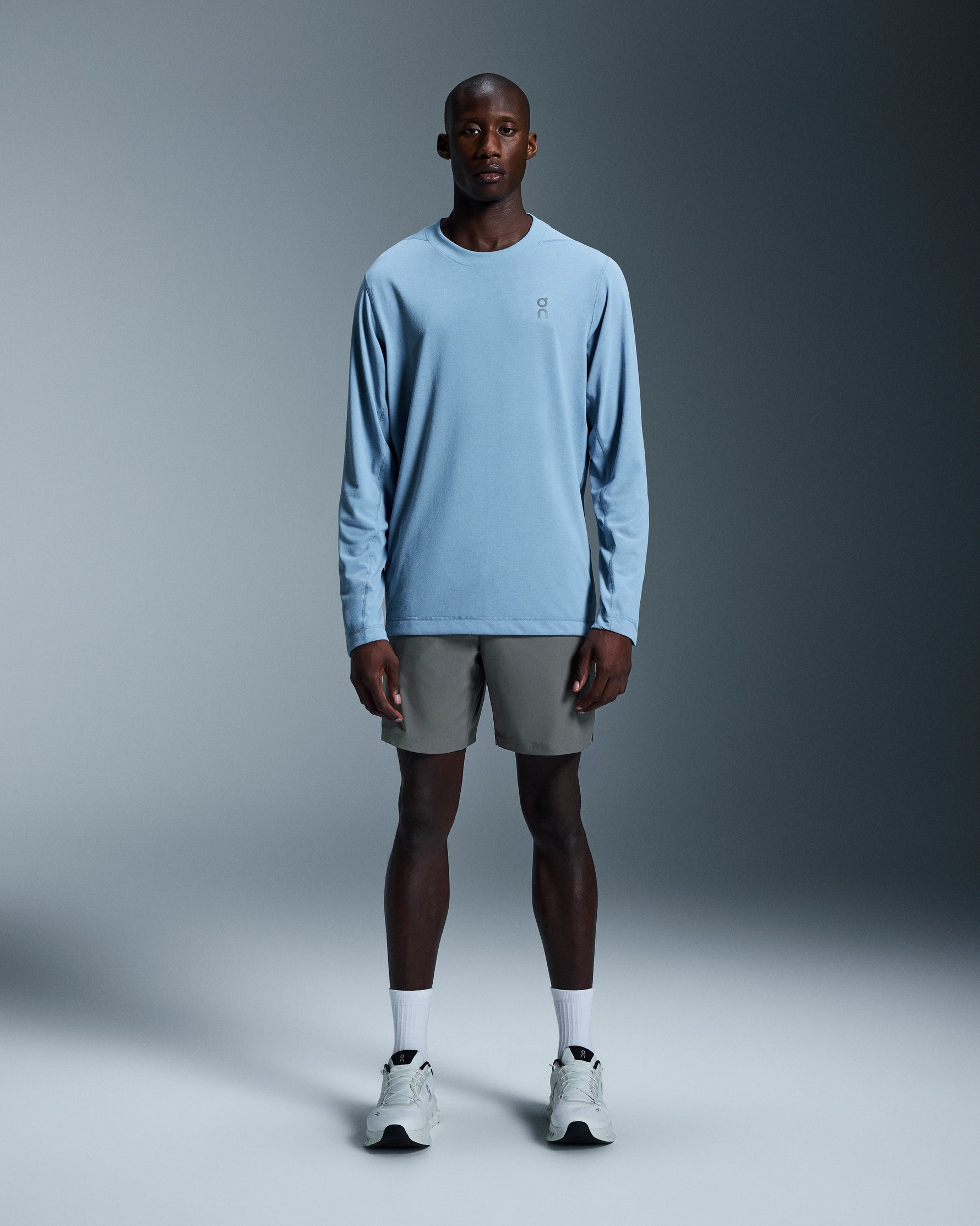 Male model wearing gray On 7-inch Core Shorts with blue long-sleeve shirt