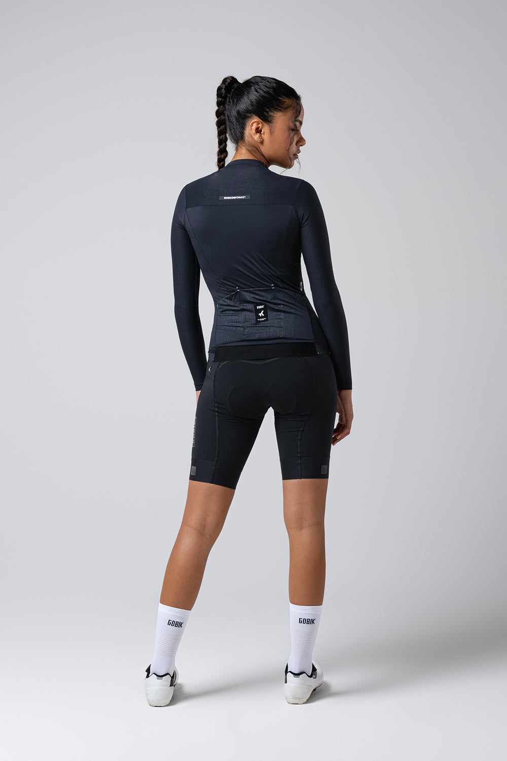 Woman wearing Gobik Avalon long sleeve cycling jersey in dark navy, back view