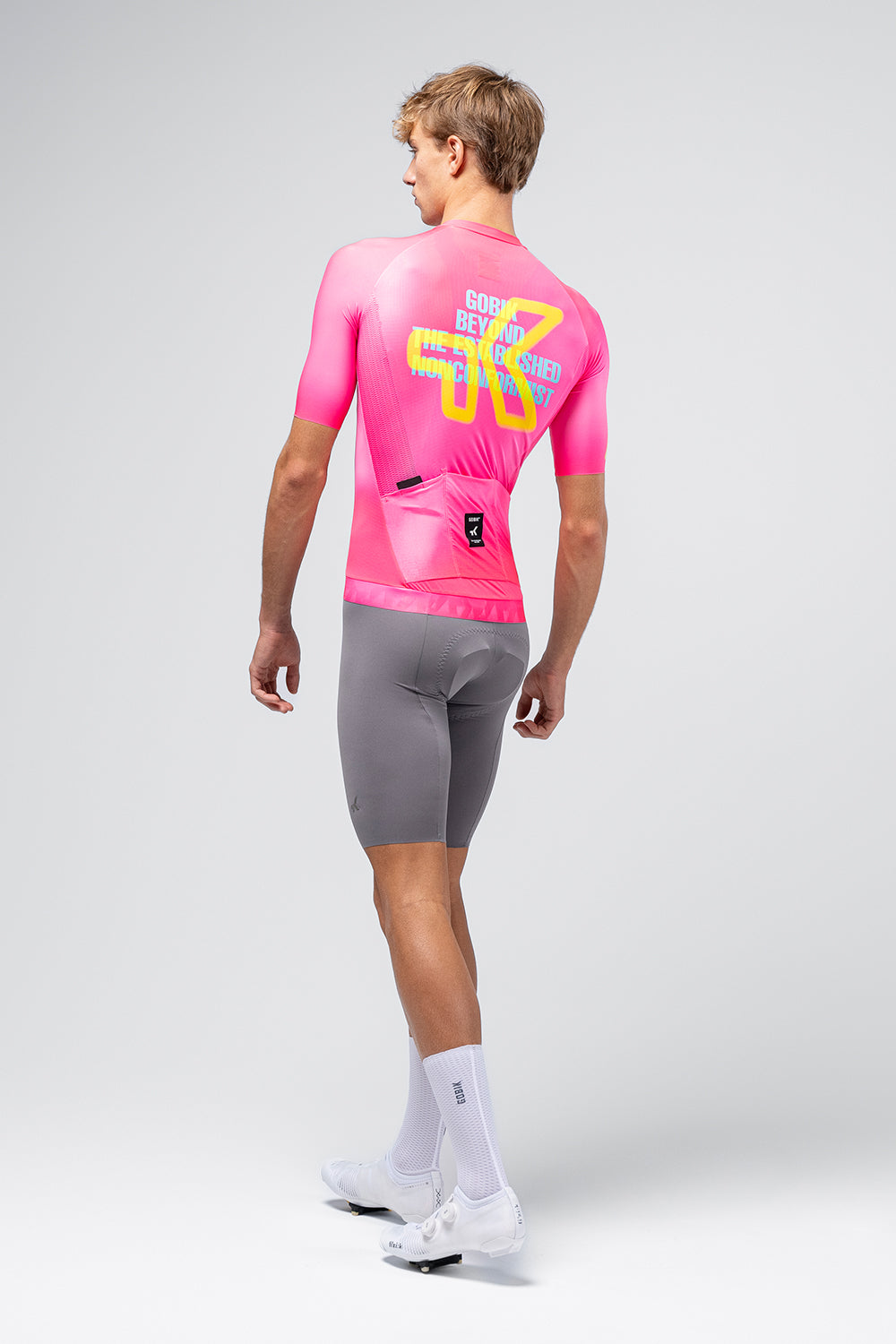 Gobik CX Pro 4.0 cycling jersey in neon pink Drip colorway, rear view on male model