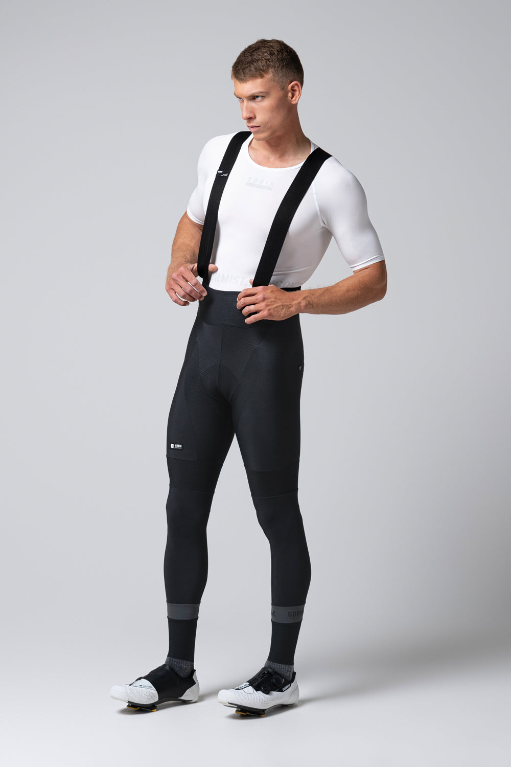 Man wearing black Gobik Absolute 7.0 bib shorts with white shirt and cycling shoes