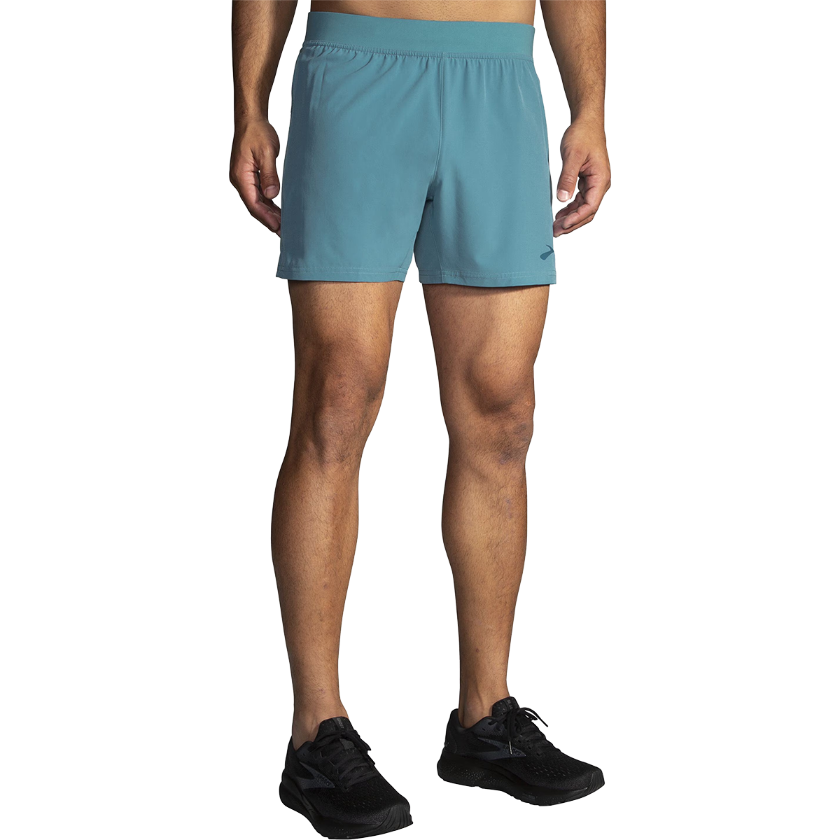 Male model wearing Brooks Sherpa 5-inch running shorts in Storm Blue, front view with black Brooks running shoes