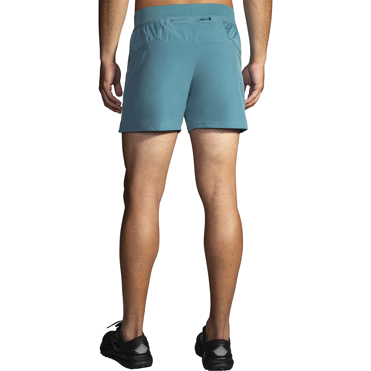 Rear view of male model wearing Brooks Sherpa 5-inch men's running shorts in Storm Blue with black Brooks shoes