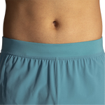 Close-up detail of Brooks Sherpa 5-inch shorts waistband in Storm Blue showing elastic gathered construction on male torso