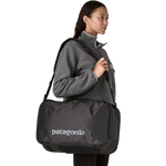 Woman wearing gray fleece carrying black Patagonia Black Hole Mini MLC bag