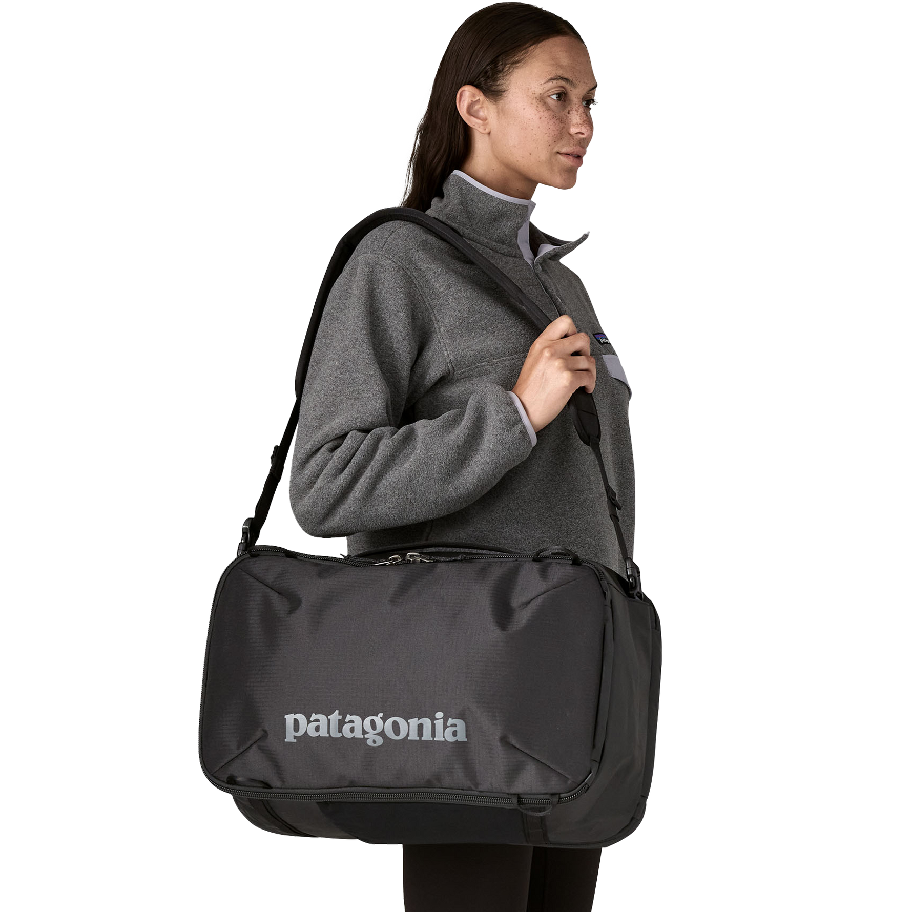 Woman wearing gray fleece carrying black Patagonia Black Hole Mini MLC bag