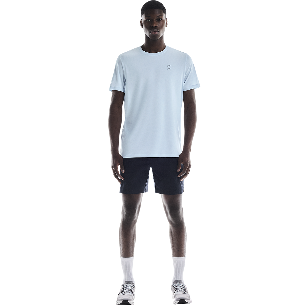 Man wearing light blue On Core-T shirt with navy shorts in studio setting