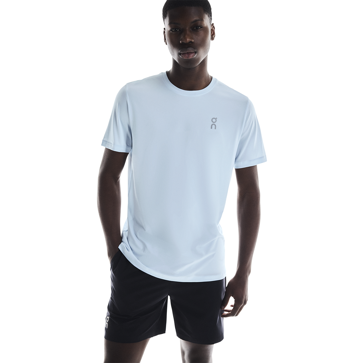 Man wearing light blue On Core-T shirt with black shorts on white background