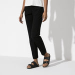 Black Birkenstock Arizona Birkibuc sandals worn with black pants on clean background