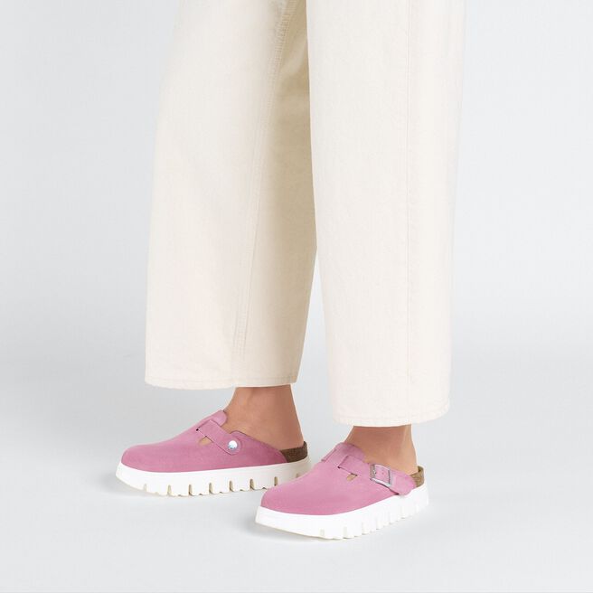 Pink Birkenstock Boston chunky suede clogs worn with cream pants on white background