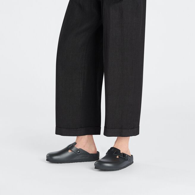 Black Birkenstock Boston Exquisite clogs worn with dark cropped pants on white background