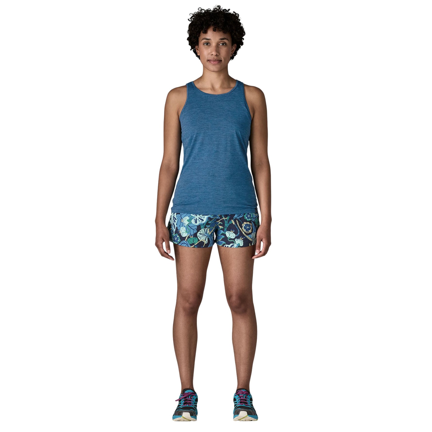 Woman wearing blue heathered tank top and floral shorts in studio photo