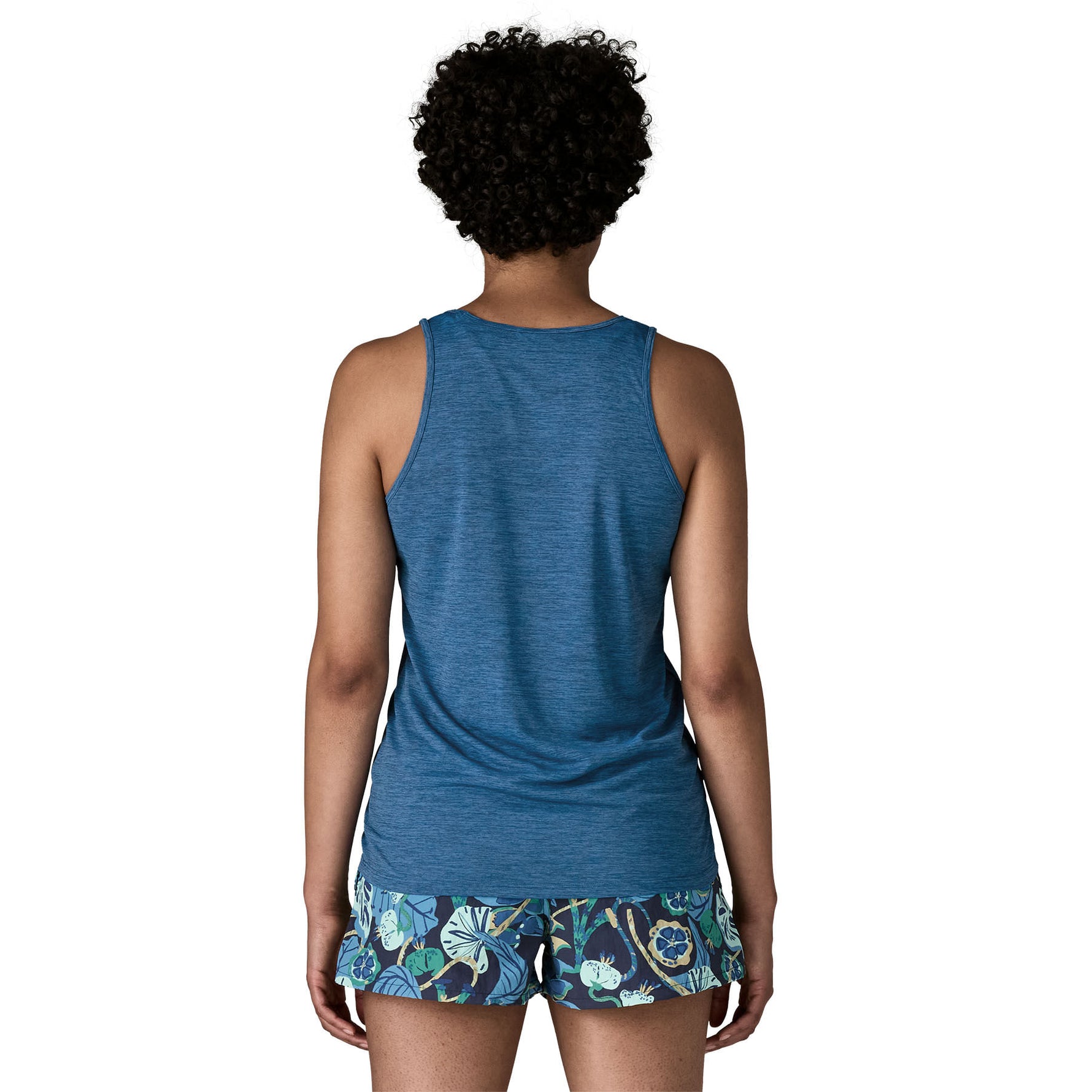 Back view of woman wearing blue Patagonia tank top with tropical print shorts