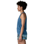 Woman in profile wearing blue heathered tank top and tropical print shorts