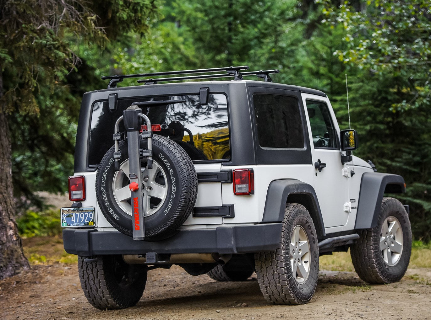 Black Yakima SpareRide bike rack mounted on white Jeep Wrangler spare tire