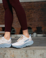 Woman wearing HOKA Clifton 10 running shoes in grout and mineral blue colorway