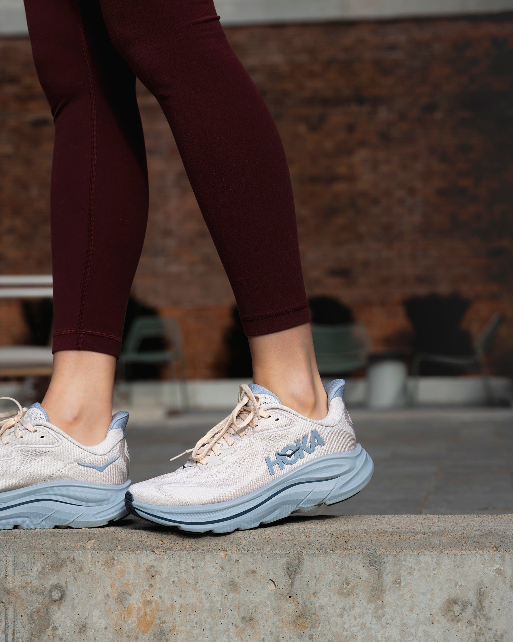 Woman wearing HOKA Clifton 10 running shoes in grout and mineral blue colorway