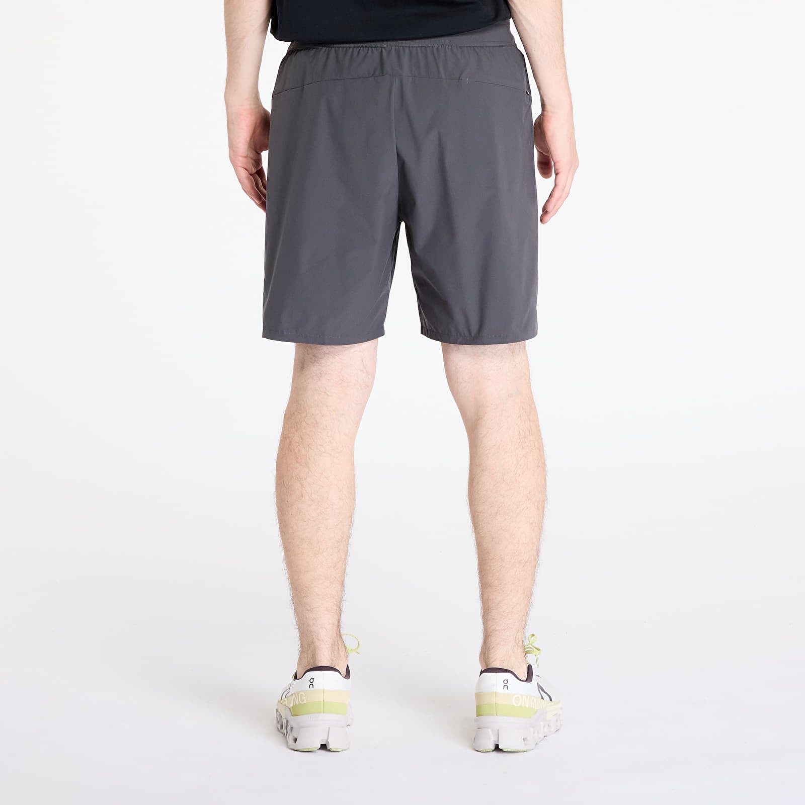 On Performance Hybrid Shorts in shadow gray worn by model, rear view