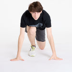 Man in running position wearing dark gray On Performance Hybrid shorts