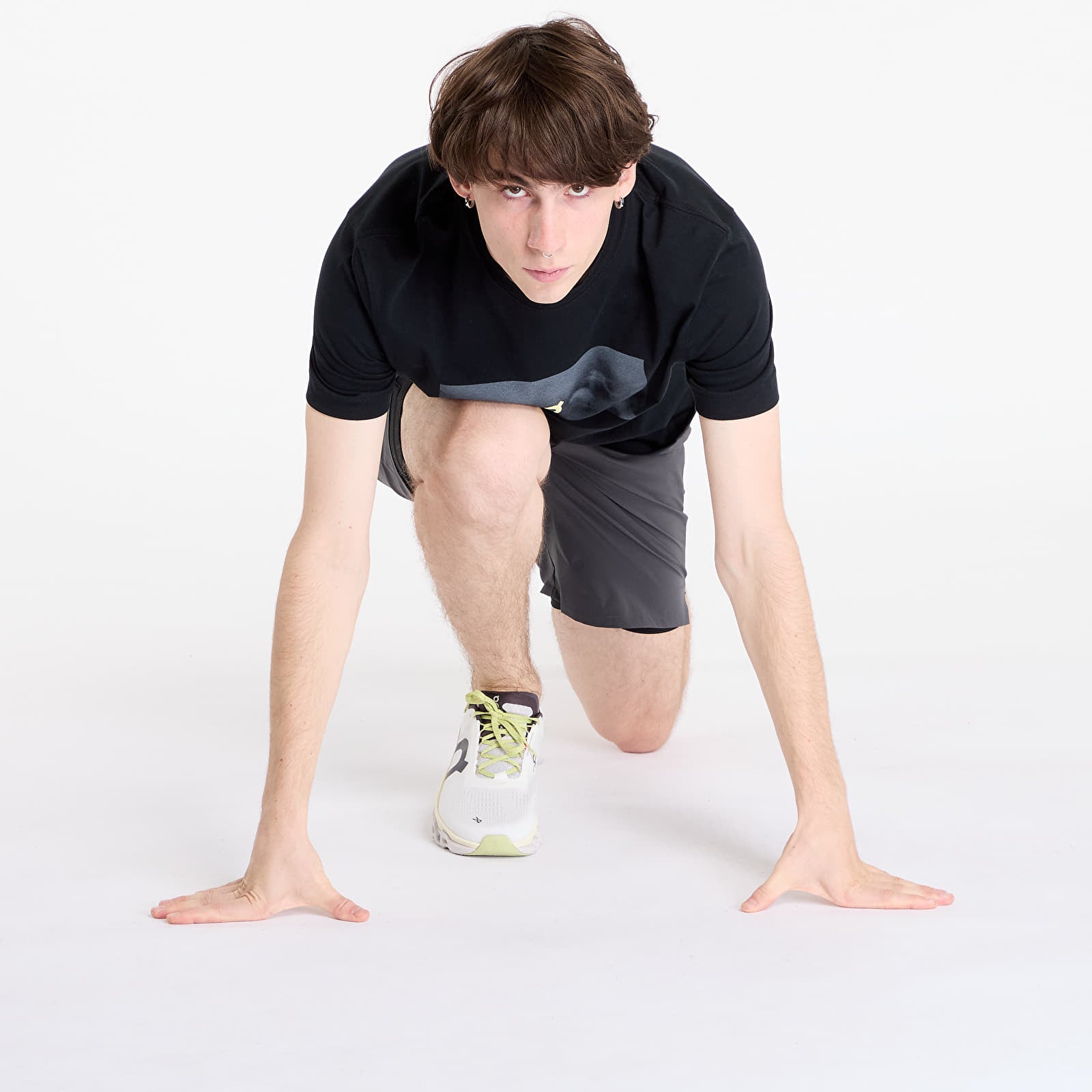 Man in running position wearing dark gray On Performance Hybrid shorts