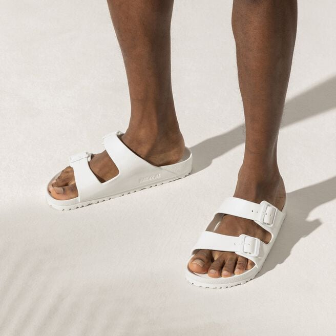 White Birkenstock Arizona EVA sandals with two buckle straps on model's feet