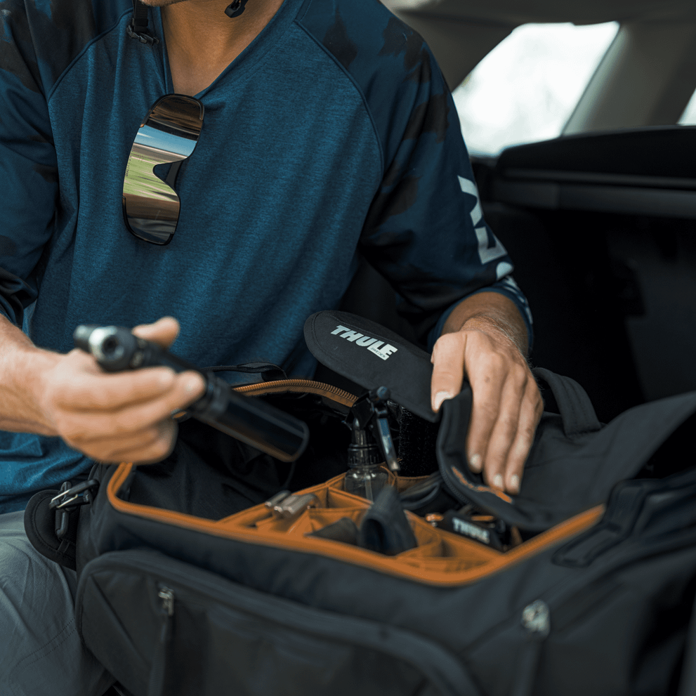 Person packing Thule bike travel bag with orange interior compartments
