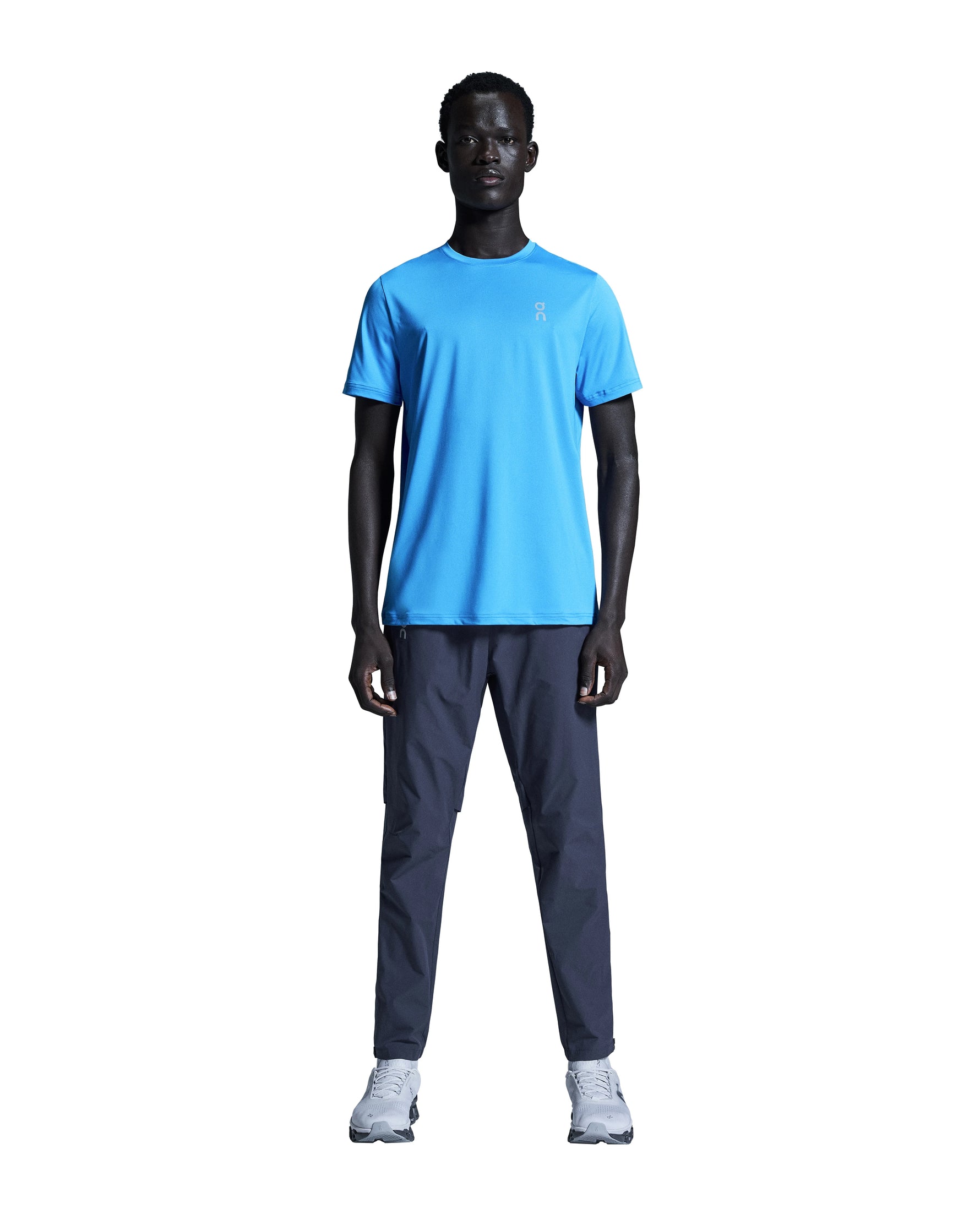 Man wearing bright blue On Core-T shirt with dark pants and sneakers