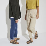 Two people wearing brown Birkenstock Arizona sandals with casual clothing against white background