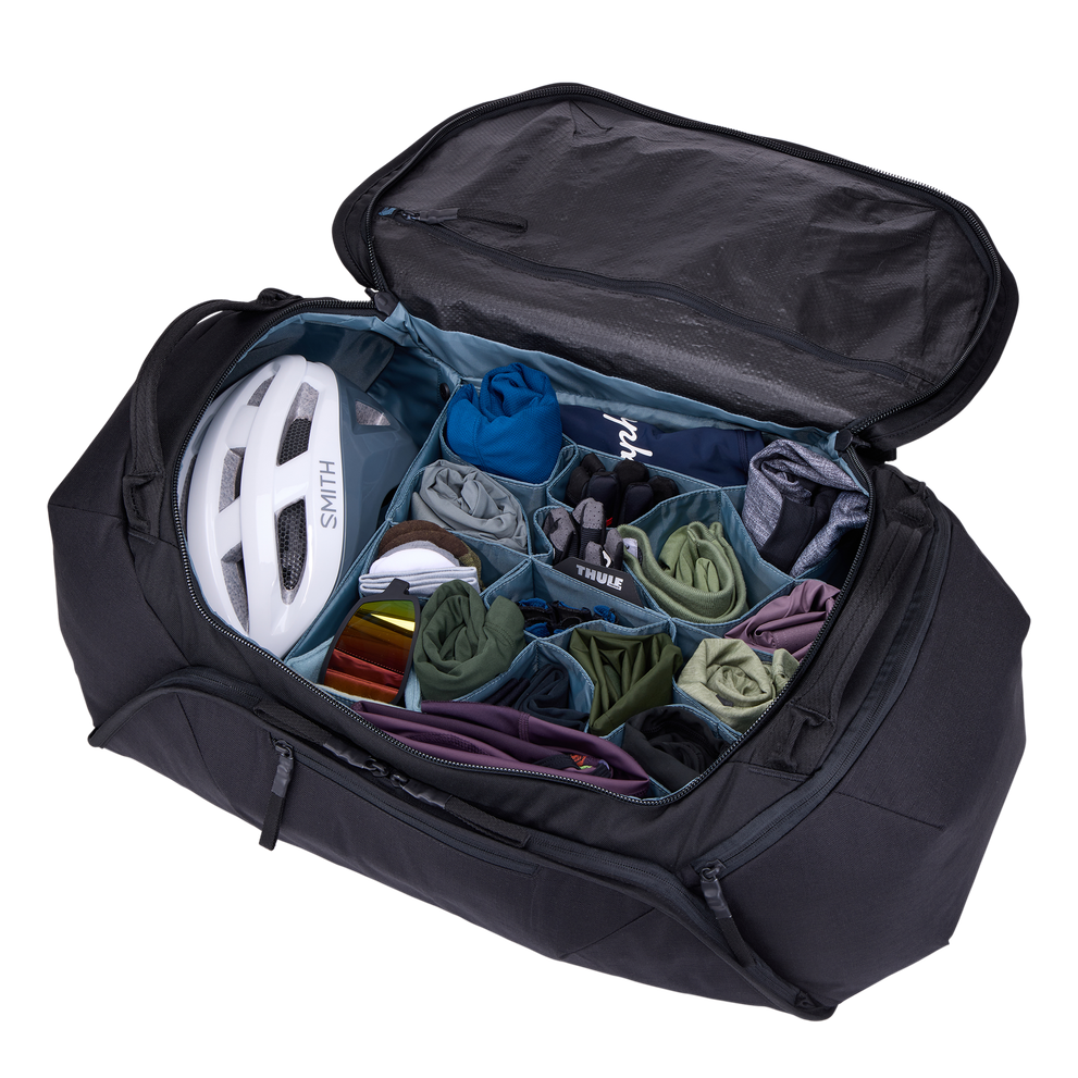 Thule Roundtrip bike duffel bag opened showing organized compartments with cycling gear and helmet