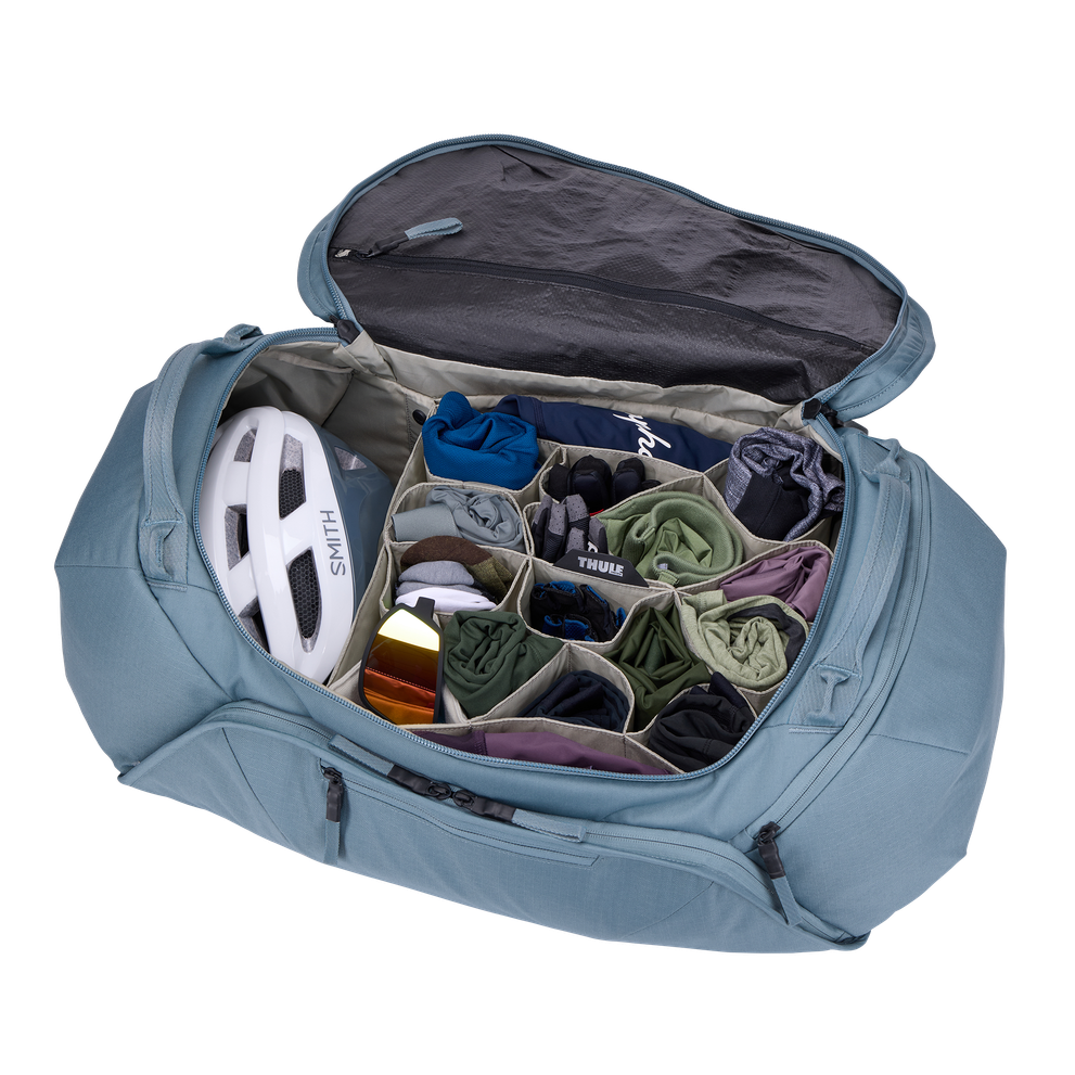 Thule Roundtrip Bike Duffel opened showing organized compartments with cycling gear and helmet