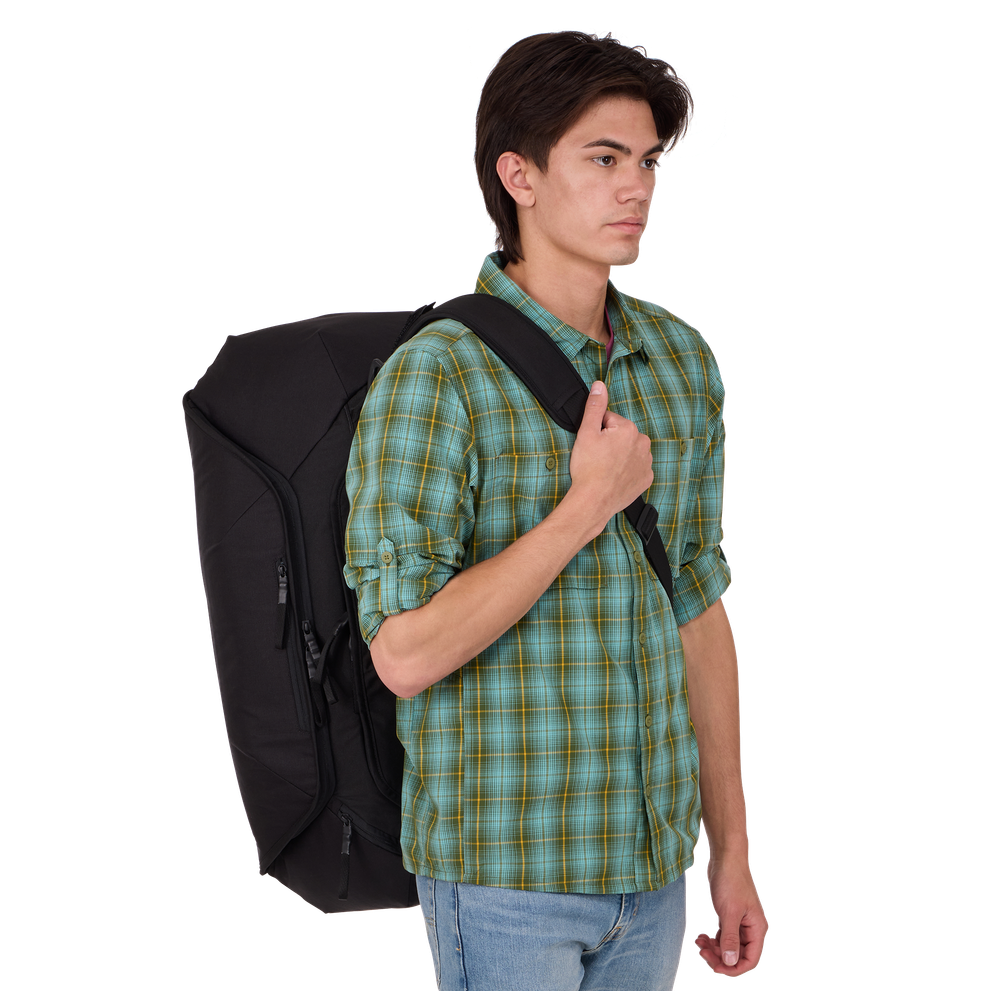 Young man wearing black Thule Roundtrip bike duffel bag on white background