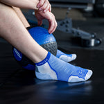 Thorlo Experia light cushion low-cut socks in blue and gray on male feet with medicine ball