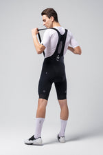 Male cyclist wearing black Gobik X bib shorts with white jersey and socks