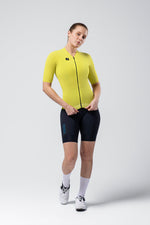 Woman wearing bright yellow-green Gobik cycling jersey with navy shorts