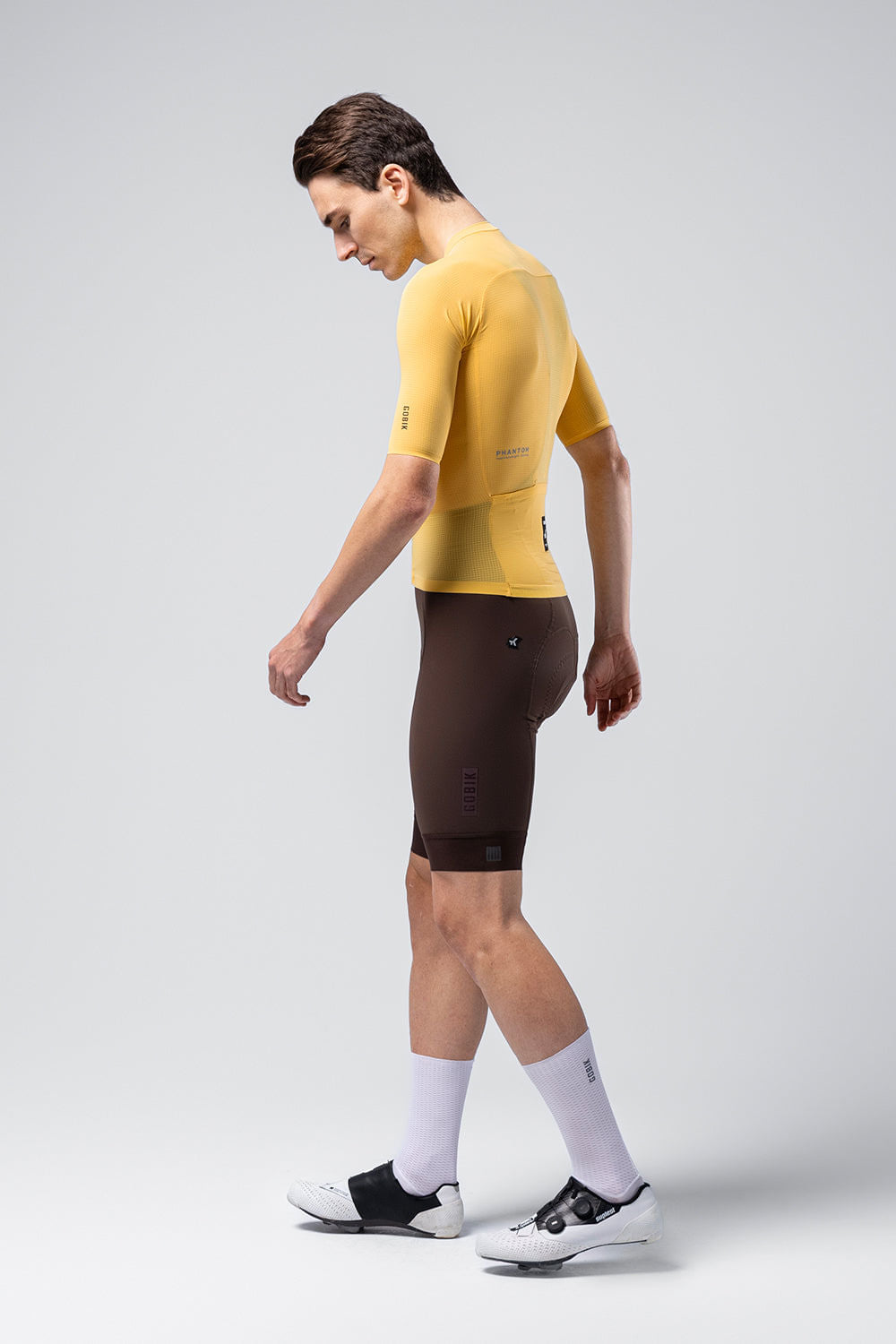 Male cyclist wearing yellow Gobik Phantom jersey with dark cycling shorts and white socks