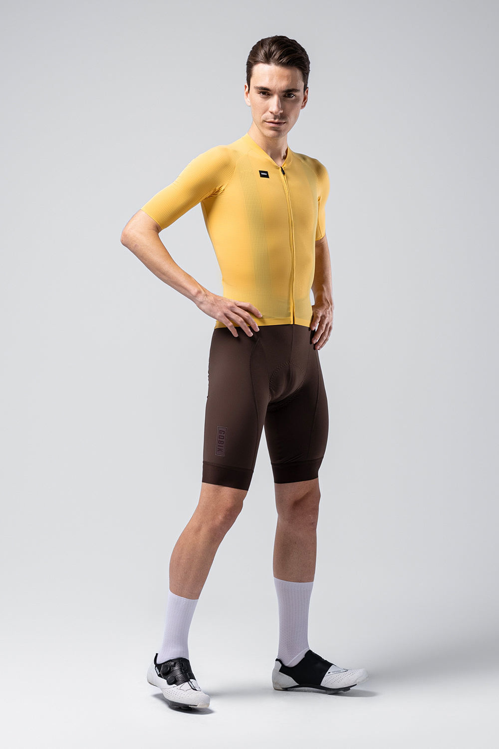 Male model wearing bright yellow Gobik Phantom cycling jersey with brown shorts