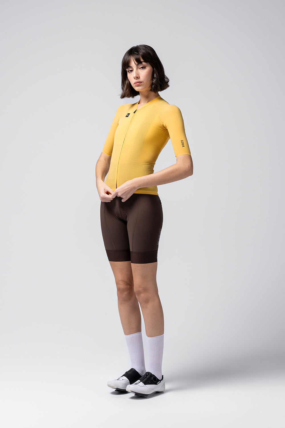Model wearing yellow Gobik Phantom cycling jersey with brown shorts in studio