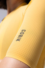 Close-up of yellow Gobik cycling jersey sleeve showing textured fabric and brand logo