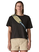Woman wearing Patagonia Atom Sling 8L crossbody bag in weathered stone olive color