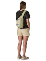 Woman wearing Patagonia Atom Sling 8L in olive green, shown from behind