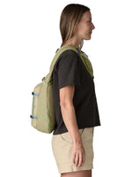 Woman wearing Patagonia Atom Sling 8L backpack in olive green color, side profile view