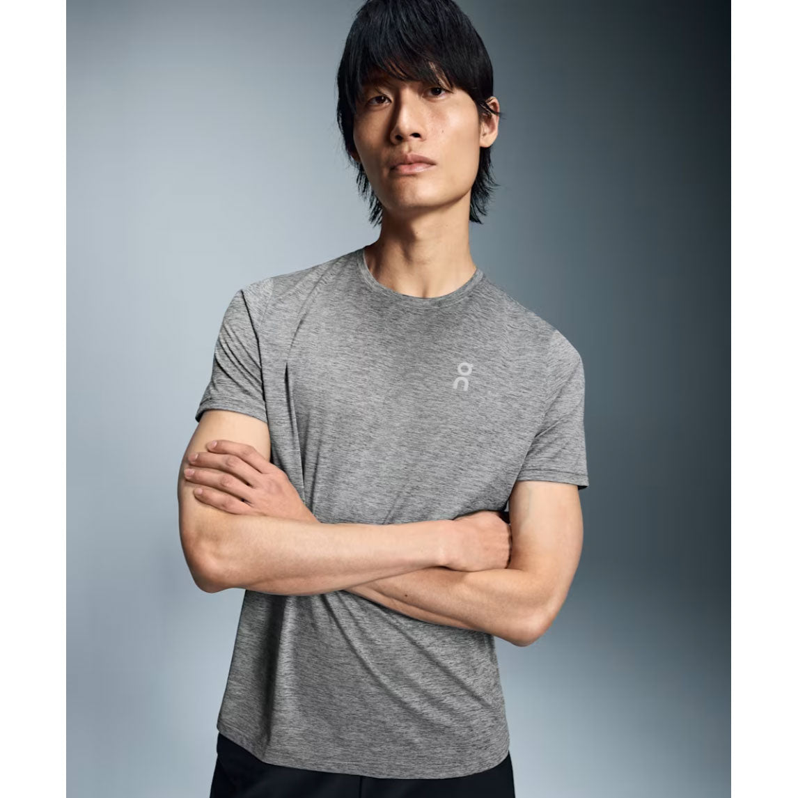 Man wearing gray heathered On Core-T shirt with arms crossed against studio background